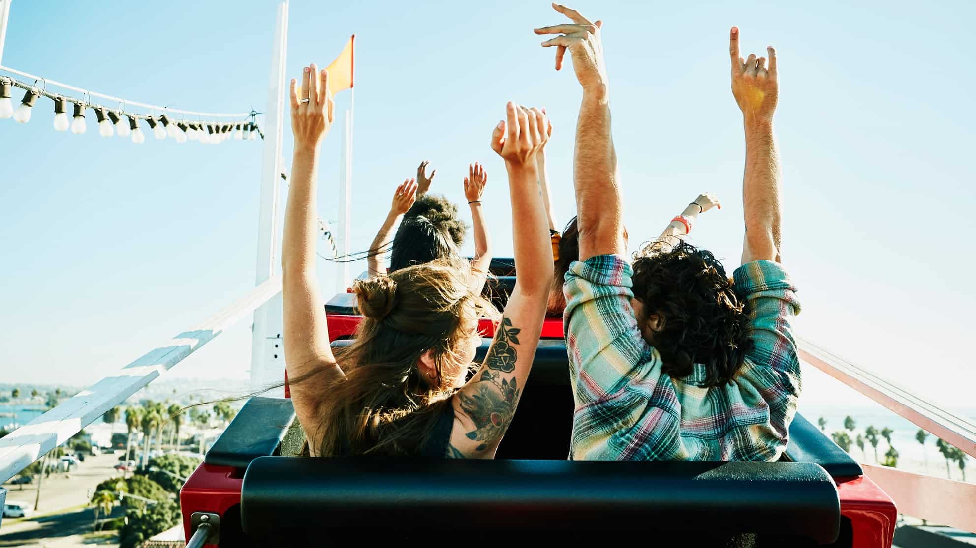 People on a rollercoaster waving hands in the air, indicating a plummeting or rising share price
