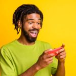 A happy man looks at his smart phone, indicating a share price rise for ASX tech shares