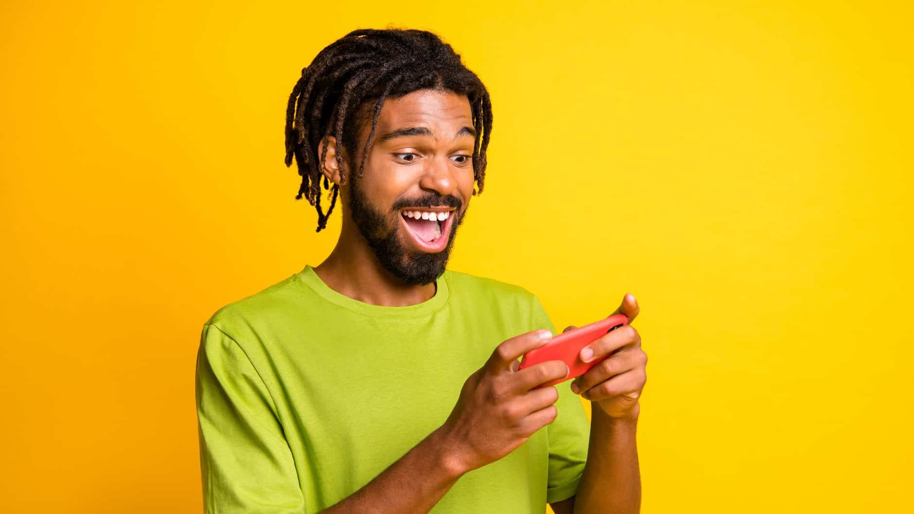 A happy man looks at his smart phone, indicating a share price rise for ASX tech shares