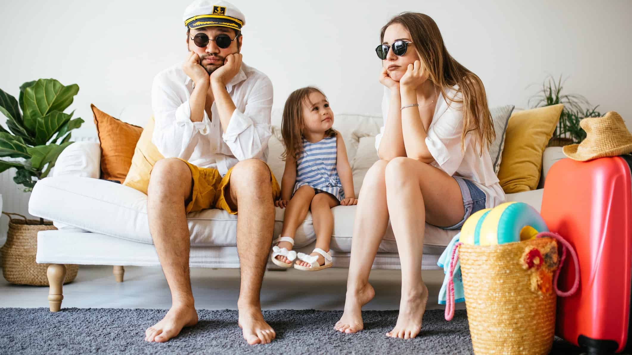 Sad family sit on the couch surrounded by bags, indicating travel restrictions hitting the share price of ASX travel companies