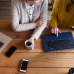 two women having a coffee whilst working from their laptops