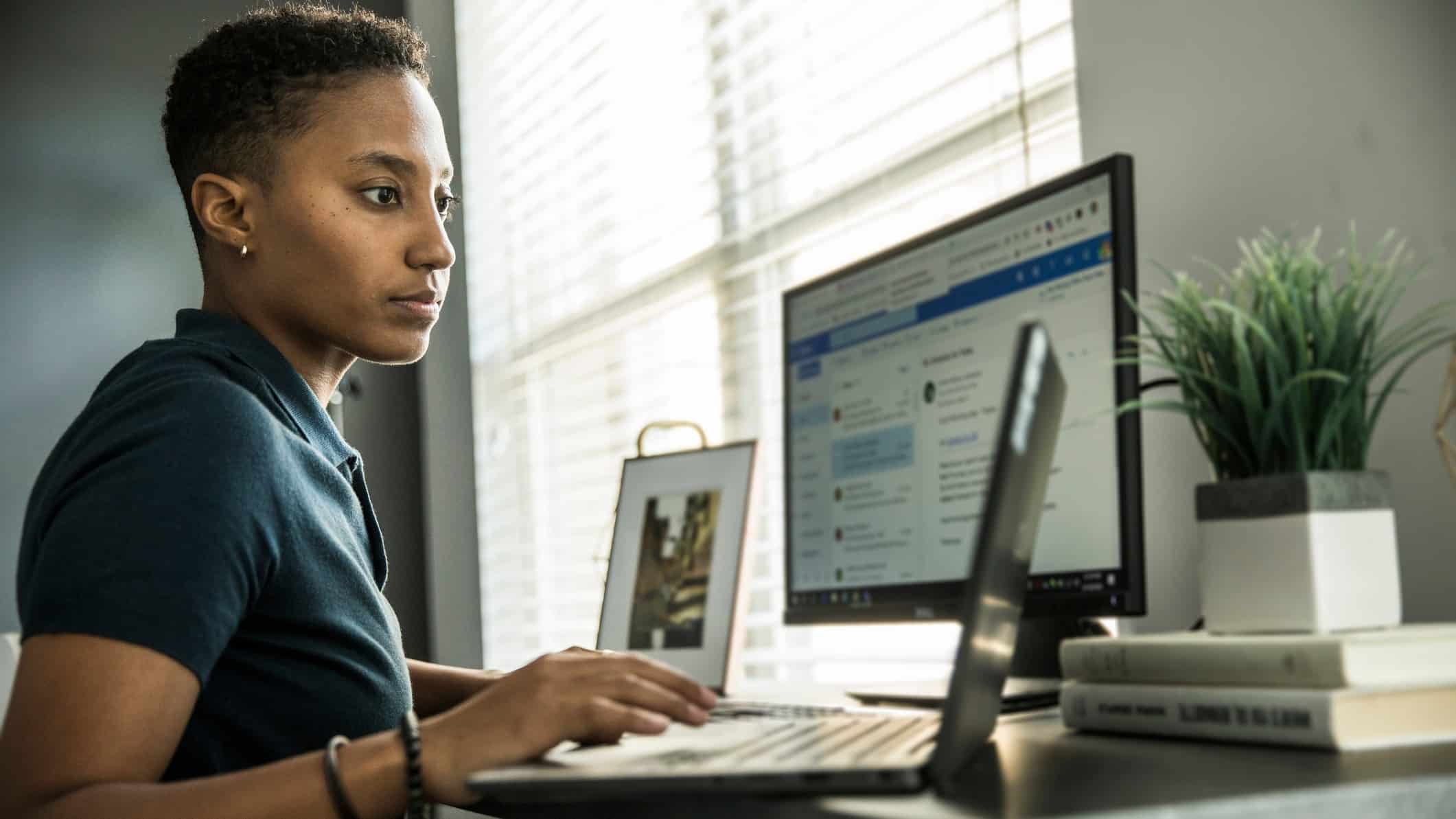 woman using a laptop with a computer open with the outlook email page browser