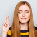 women with her fingers crossed and eyes shut