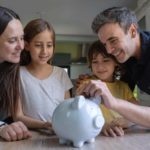 parents putting money in piggy bank for kids future