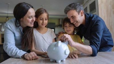 parents putting money in piggy bank for kids future