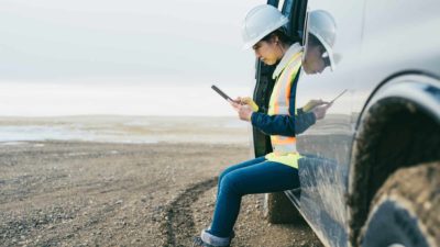 Female oil worker uses mobile phone at mine site
