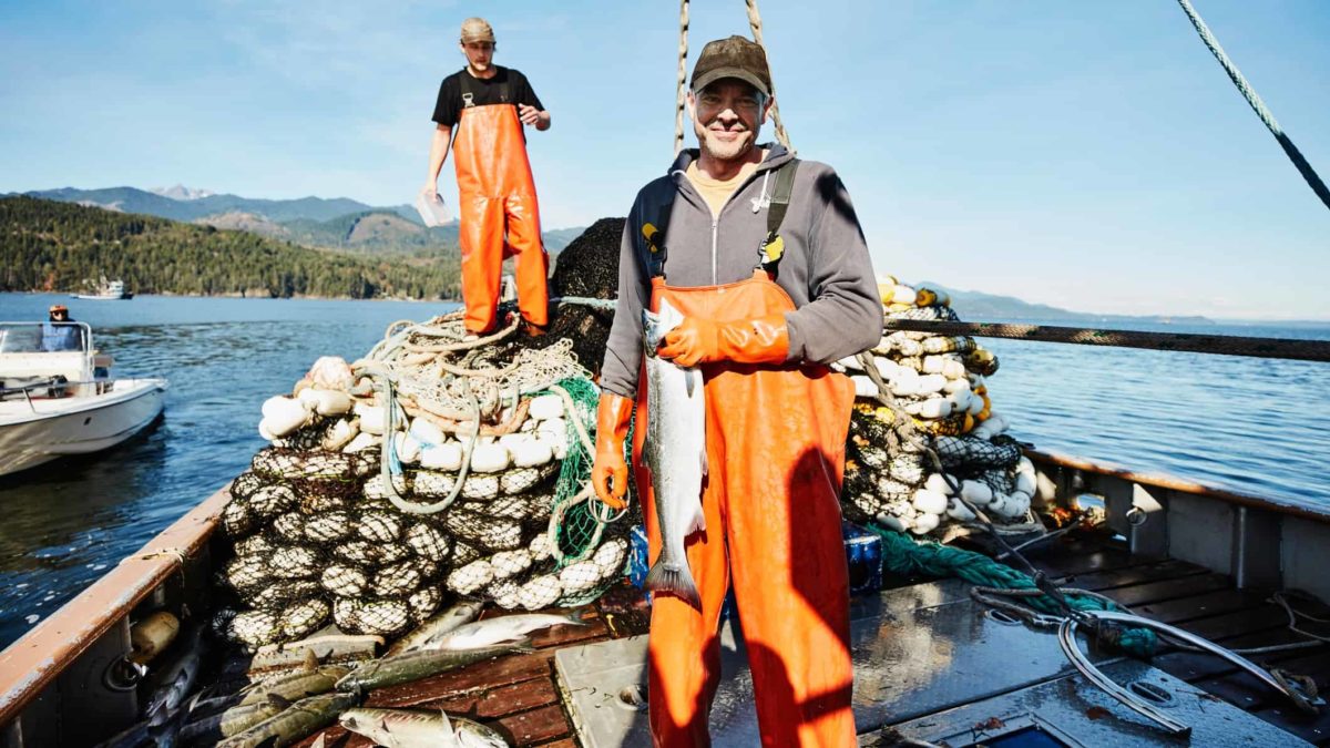 Fisherman holding salmon on the deck of a boat