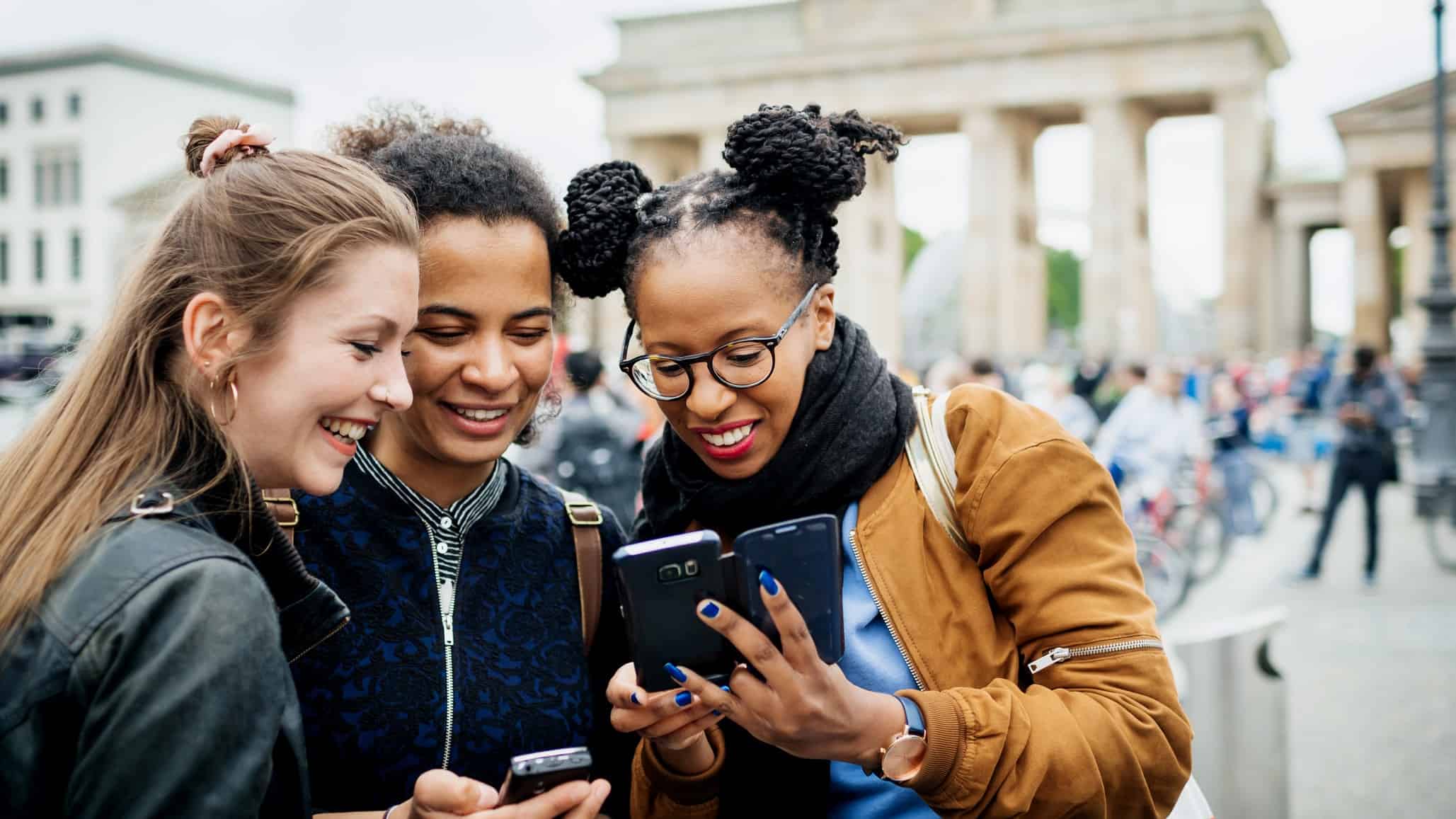 three women with smartphone technology in European street scene