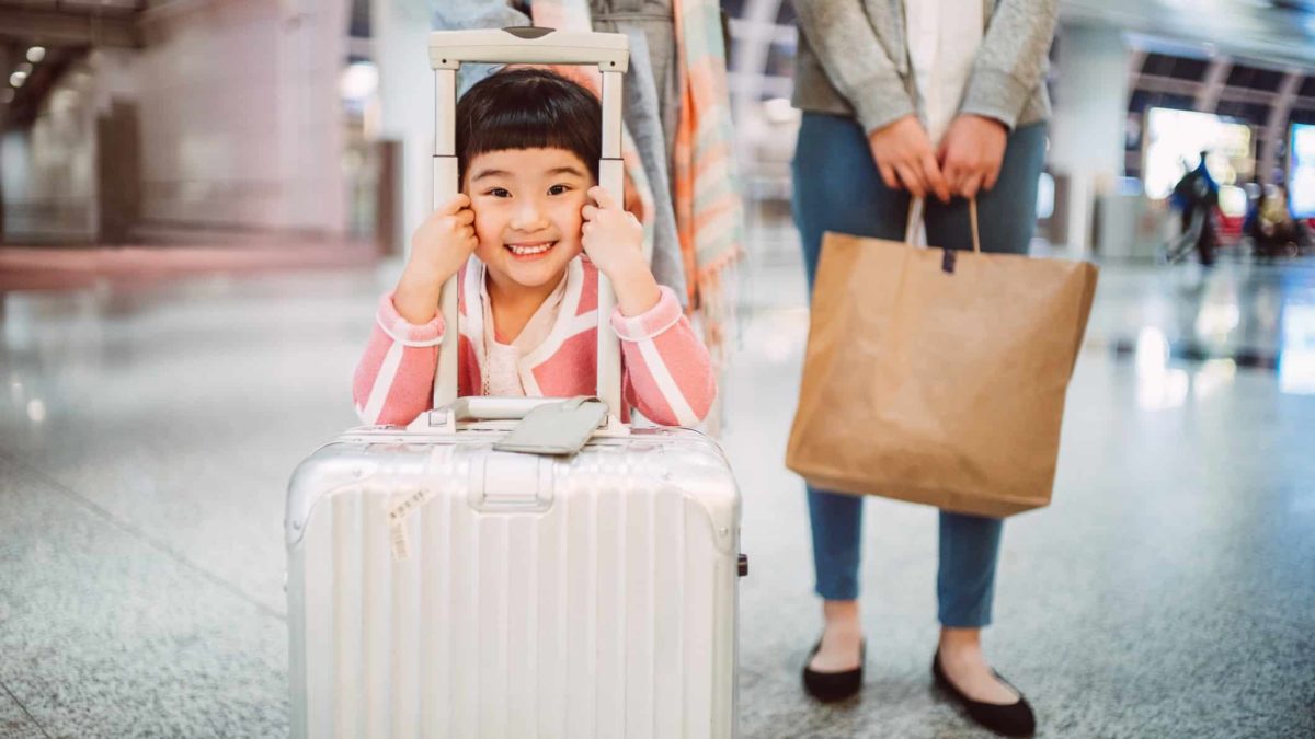 Happy girl with luggage at airport