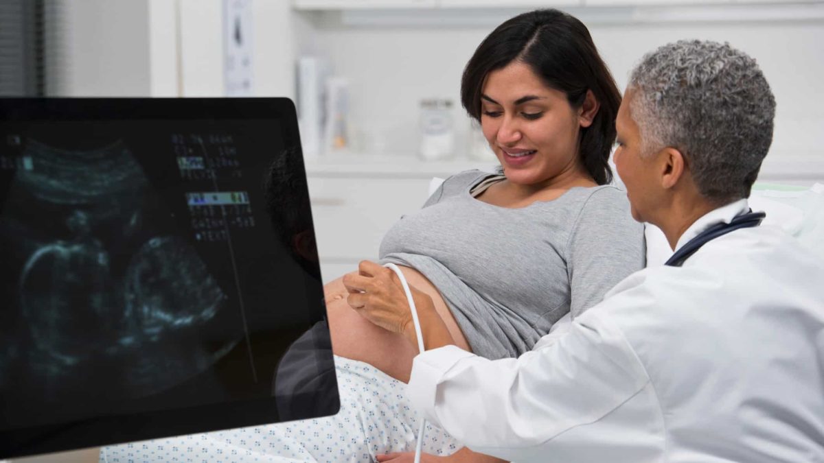 Doctor performing an ultrasound on pregnant woman