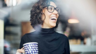 Womann holding a coffee mug and smiling.