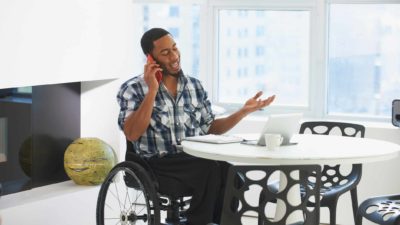wheelchair user in an office talking on mobile phone