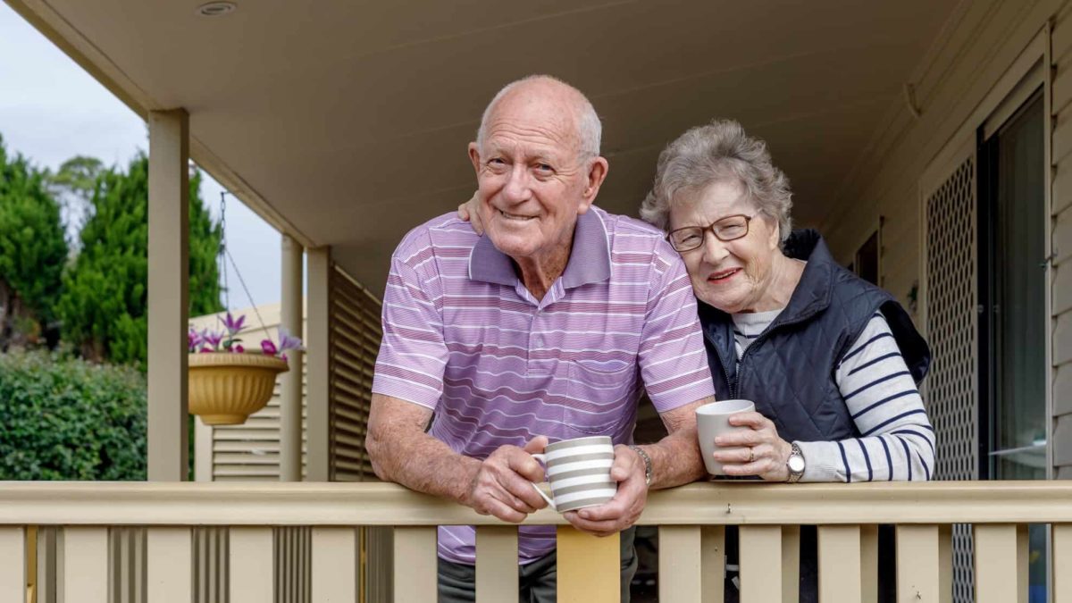 A elder man and woman lean over their balcony with a cuppa, indicating share rpice movement for ASX retirement shares