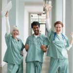 three excited doctors with hands in the air