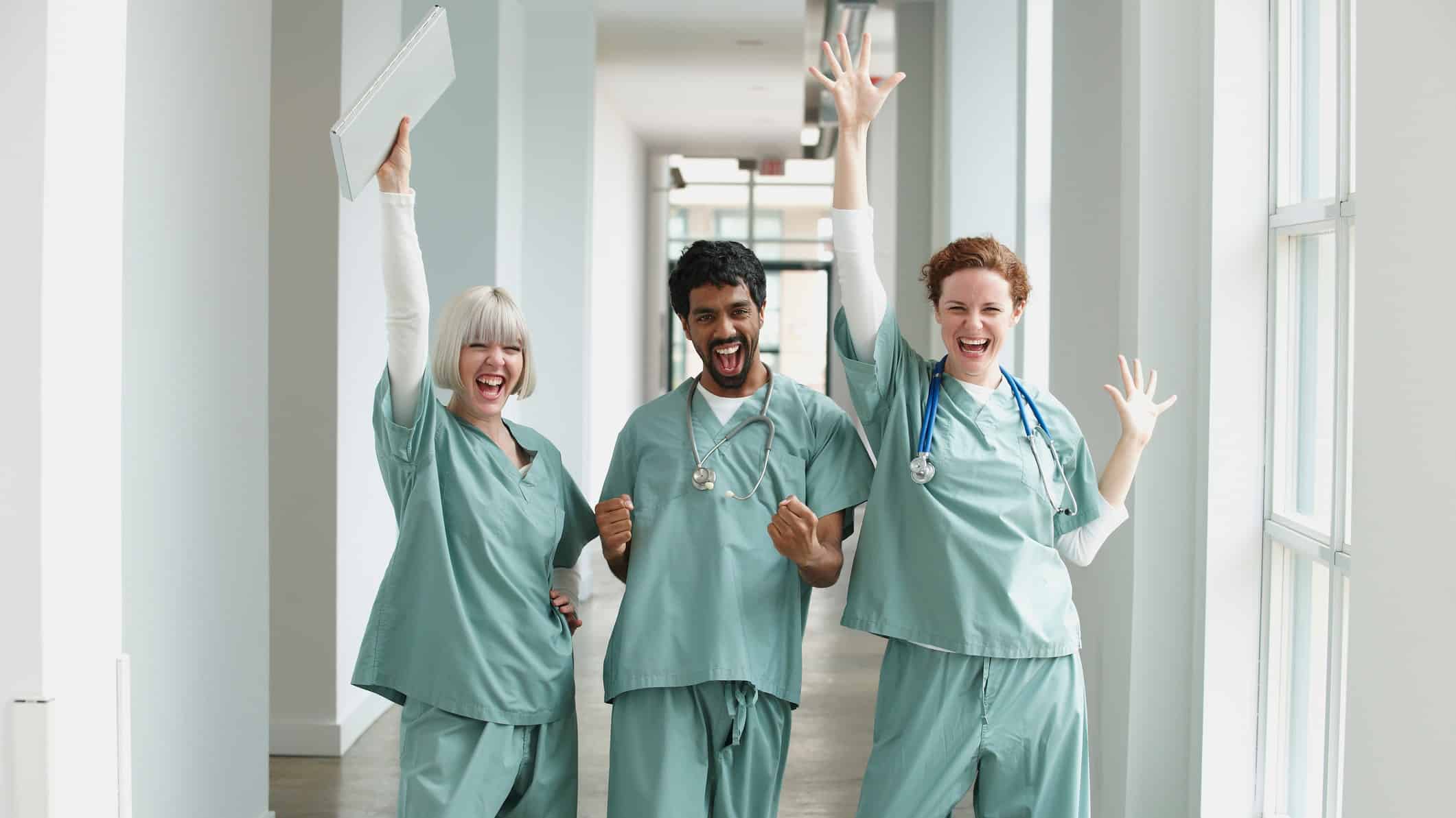 three excited doctors with hands in the air