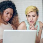 two women looking intently at computer screen