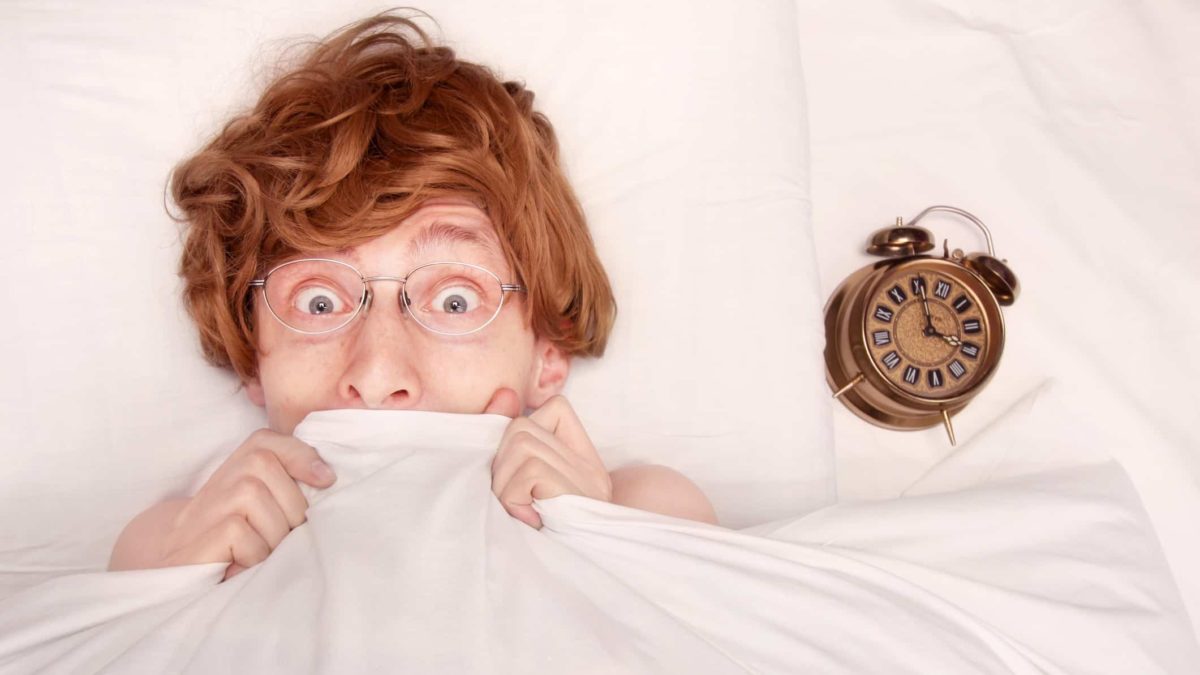 nerdy looking guy with glasses peeking out from under bed sheets