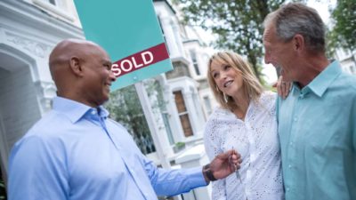real estate agent handing over keys to couple having just bought new home