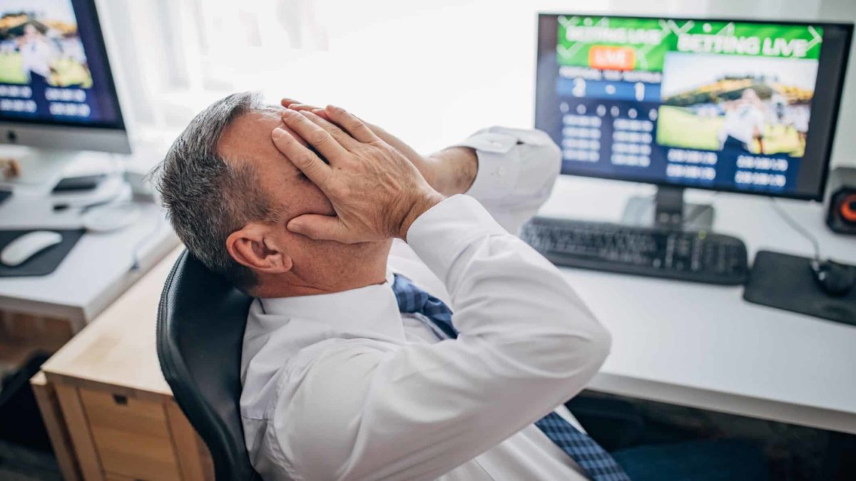 Man sitting at desk in front of PC with his head in hands after looking atA worried man holds his head and look at his computer as the Megaport share price crashes today
