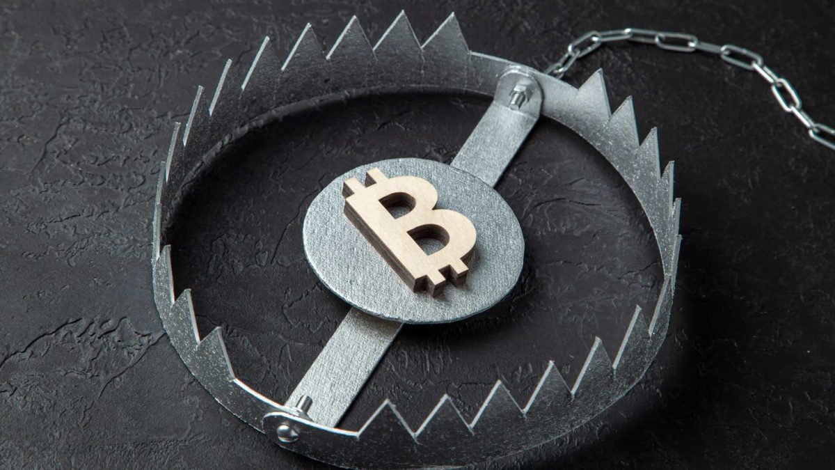 A bitcoin symbol sits inside the teeth of an animal trap, indicating the dangers of investing in cryptocurrencies