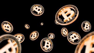 Bitcoin cryptocurrency coins bounce around on a black background, indicating a volatile price