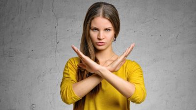 A woman crosses her hands in front of her body in a defensive stance indicating a trading halt.