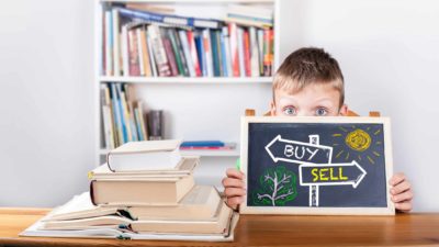 boy holding chalk board depicting buy and sell options for ASX shares