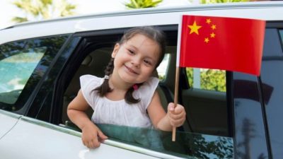 girl holding out a Chinese flag through a window