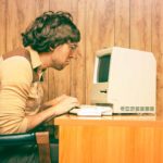 A retro image of a computer nerd trying to figure out his computer technology, indicating a falling share price in ASX tech shares