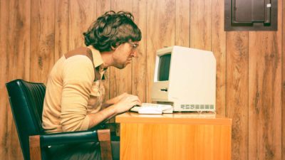 A retro image of a computer nerd trying to figure out his computer technology, indicating a falling share price in ASX tech shares