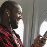 Happy aeroplane passenger using his phone and listening to music.