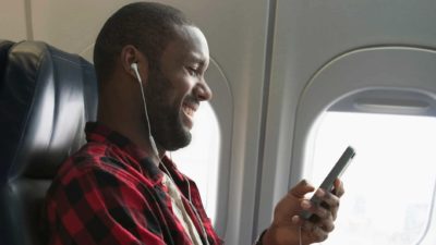 Happy aeroplane passenger using his phone and listening to music.