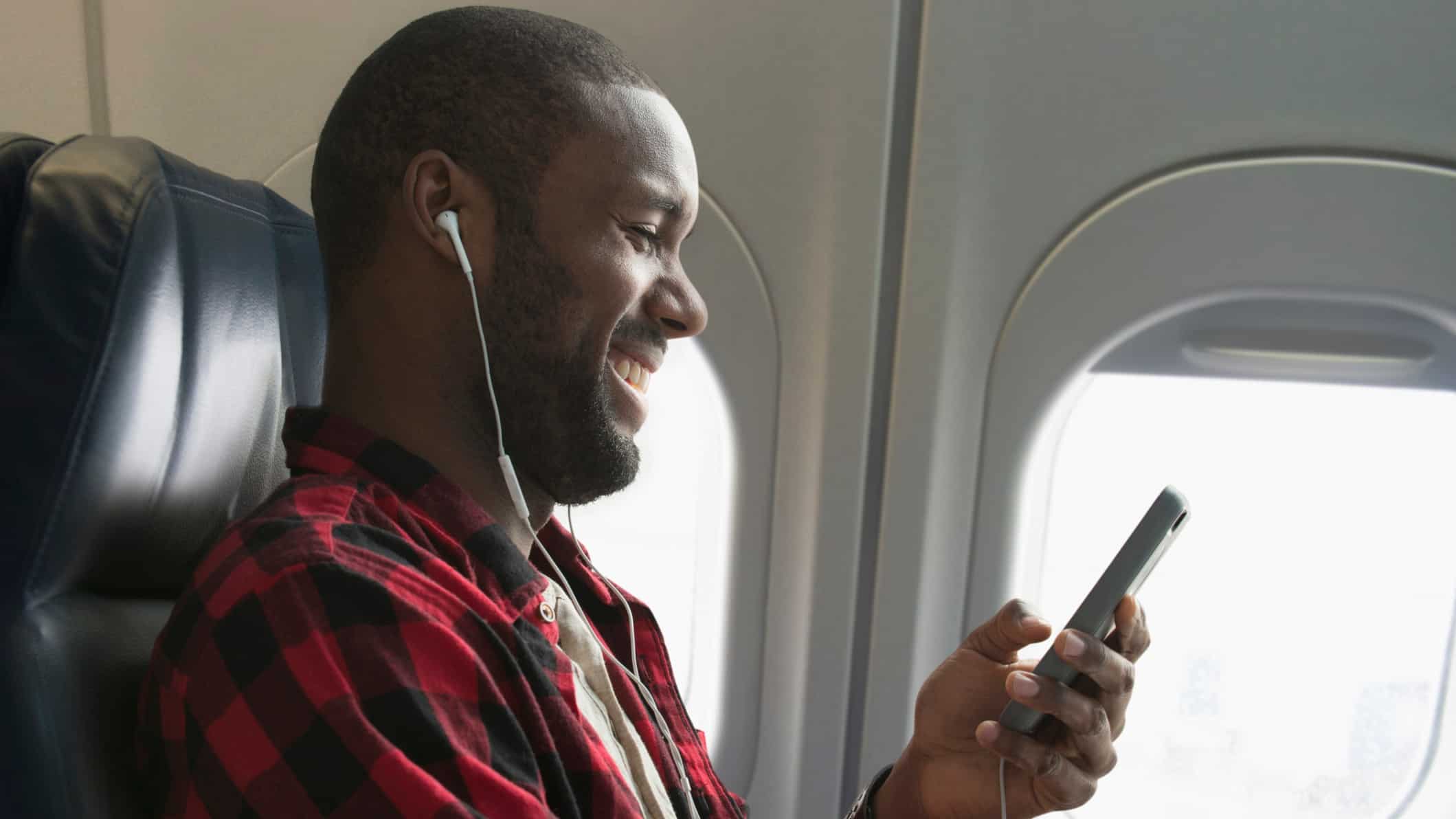 Happy aeroplane passenger using his phone and listening to music.
