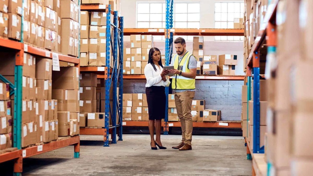 man and woman have a discussion on a tablet in a transportation warehouse