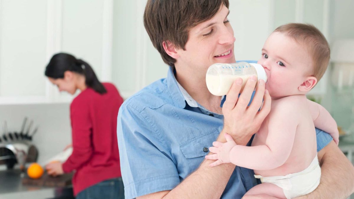 happy man feeding baby in the home kitchen