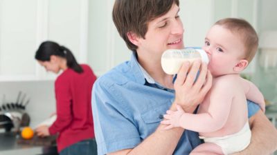 happy man feeding baby in the home kitchen