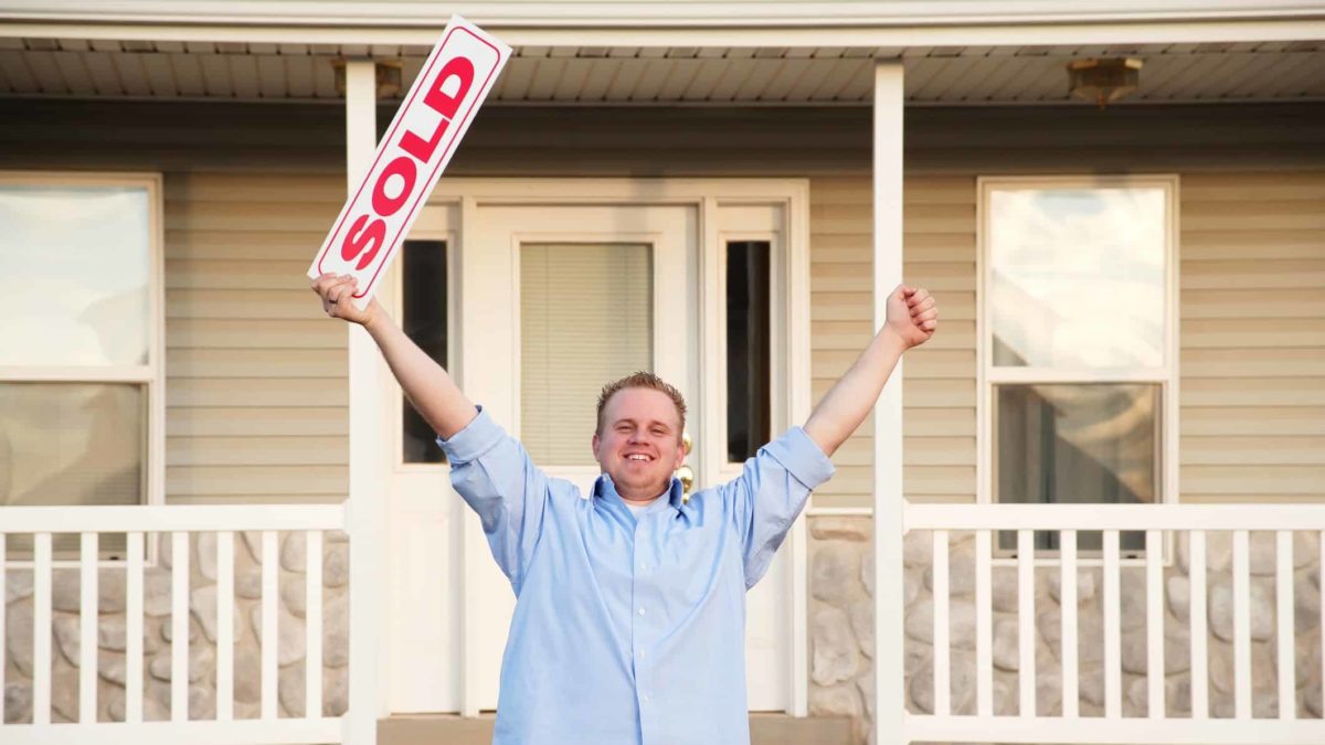 Stockland dividend share price man happy at property being sold with arms raised in the air
