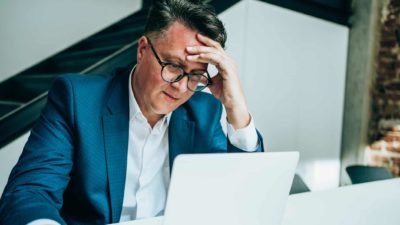 A shocked and stressed man looking at his laptop and trying to absorb bad news about the Netwealth share price falling