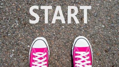 Two red sneakers on the start line, indicating a new investor learning about share price movement and how to invest