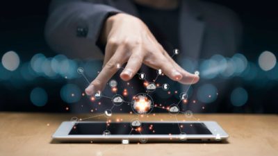 A hand hovers over a laptopn sparkling with tech symbols, indicating ASX technology shares