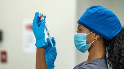 woman injecting the syringe into the vaccine solution