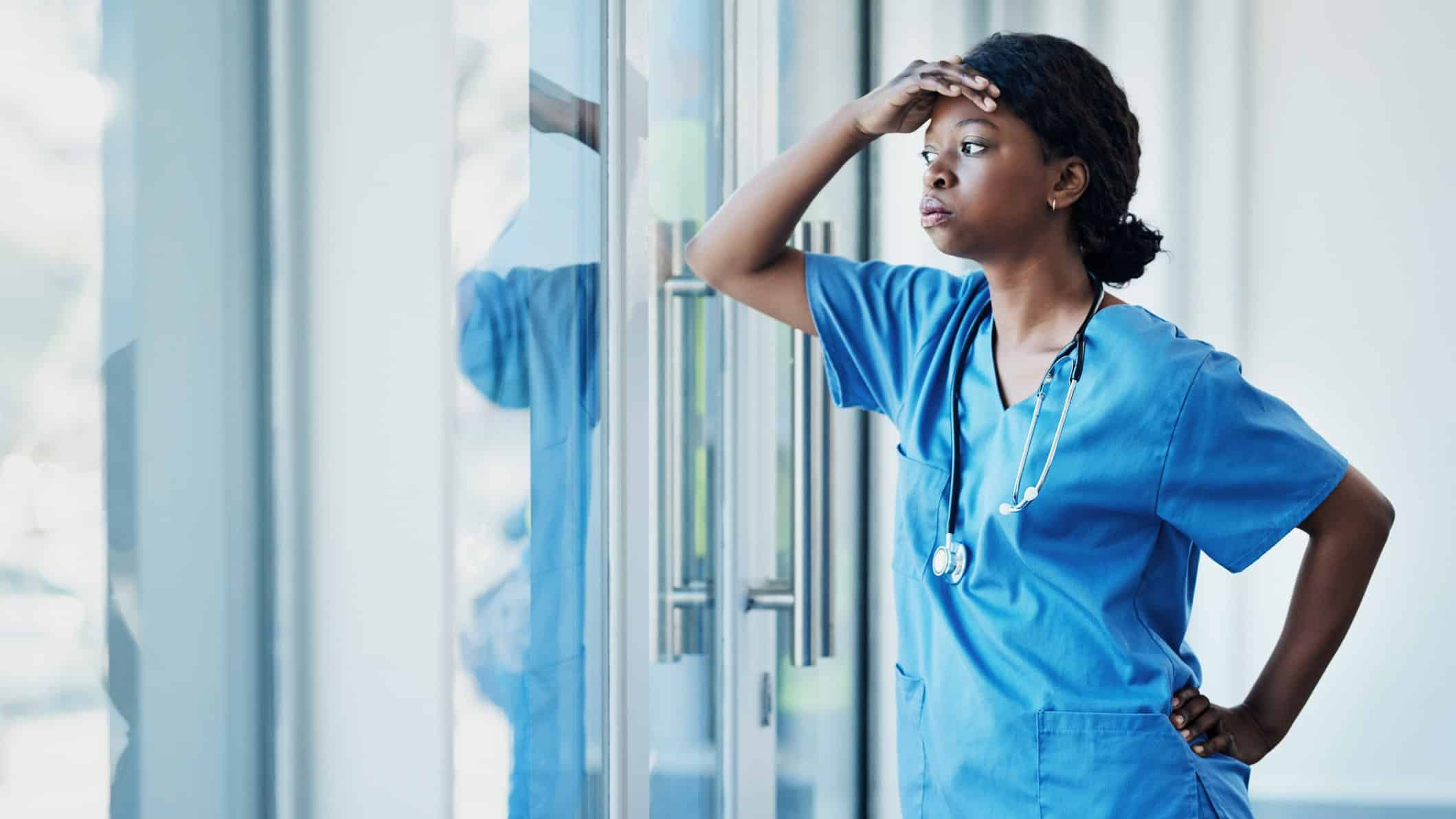 worried doctor looking through glass door representing falling share price