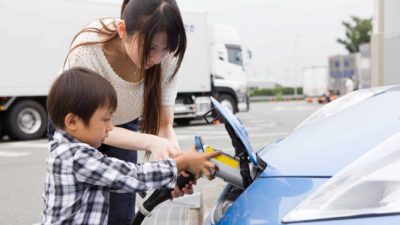 Boy and woman charge electric vehicle