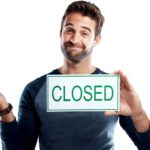 person shrugging holding a sign saying closed.