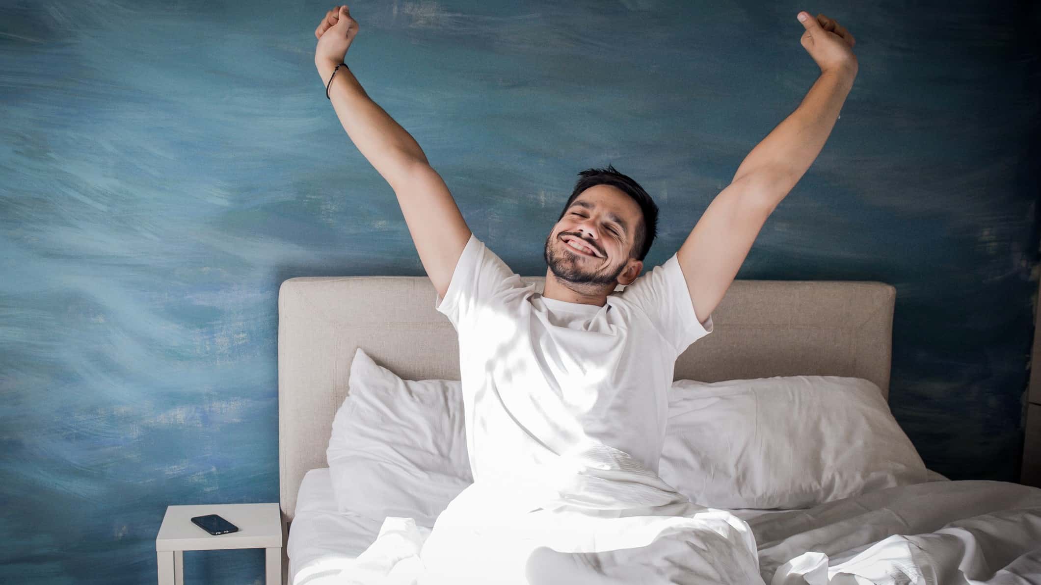 person waking up happy and stretching in bed