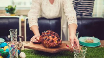 a woman present a roasted ham on a celebratory table.