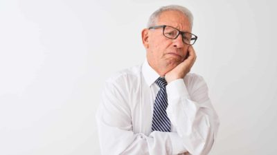 executive in shirt and tie holding chin in hand looking disappointed because of slashed dividend payouts