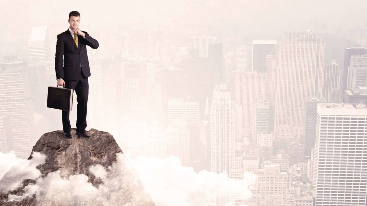 person standing tall on a mountain peak above city scene