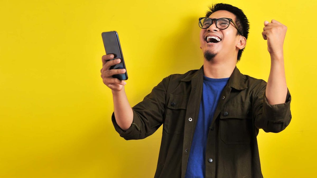 Man holding phone celebrating share price rise