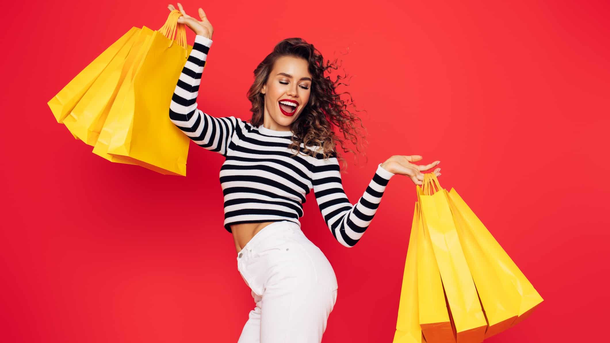 a happy young woman holding multiple shopping bags